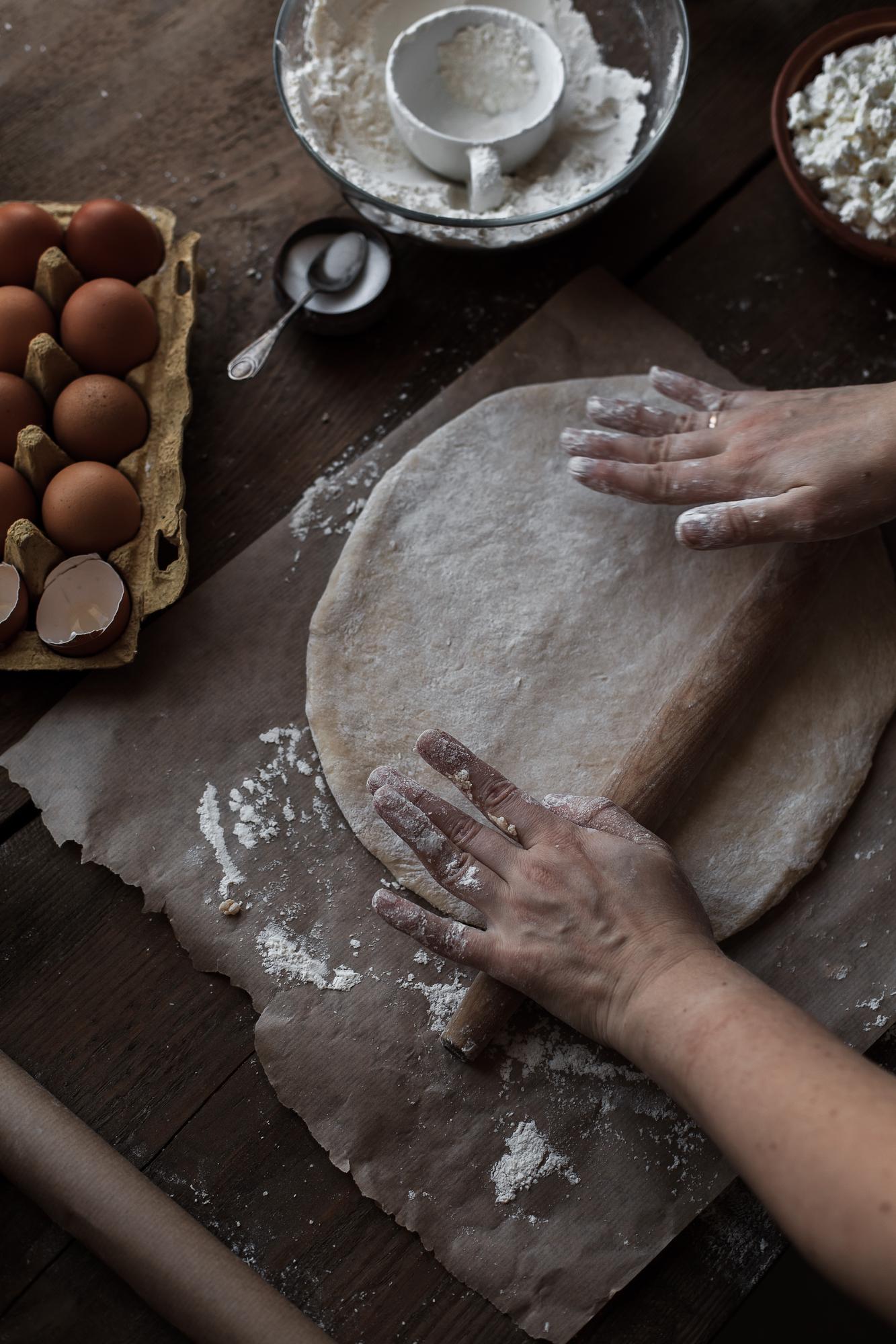 Close-up of hands kneading dough on floured surface