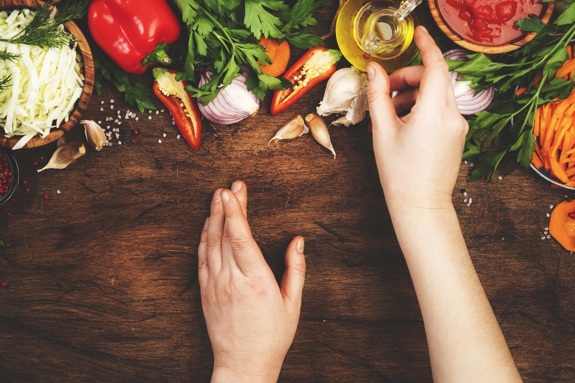 Hands sprinkling finishing salt over roasted vegetables
