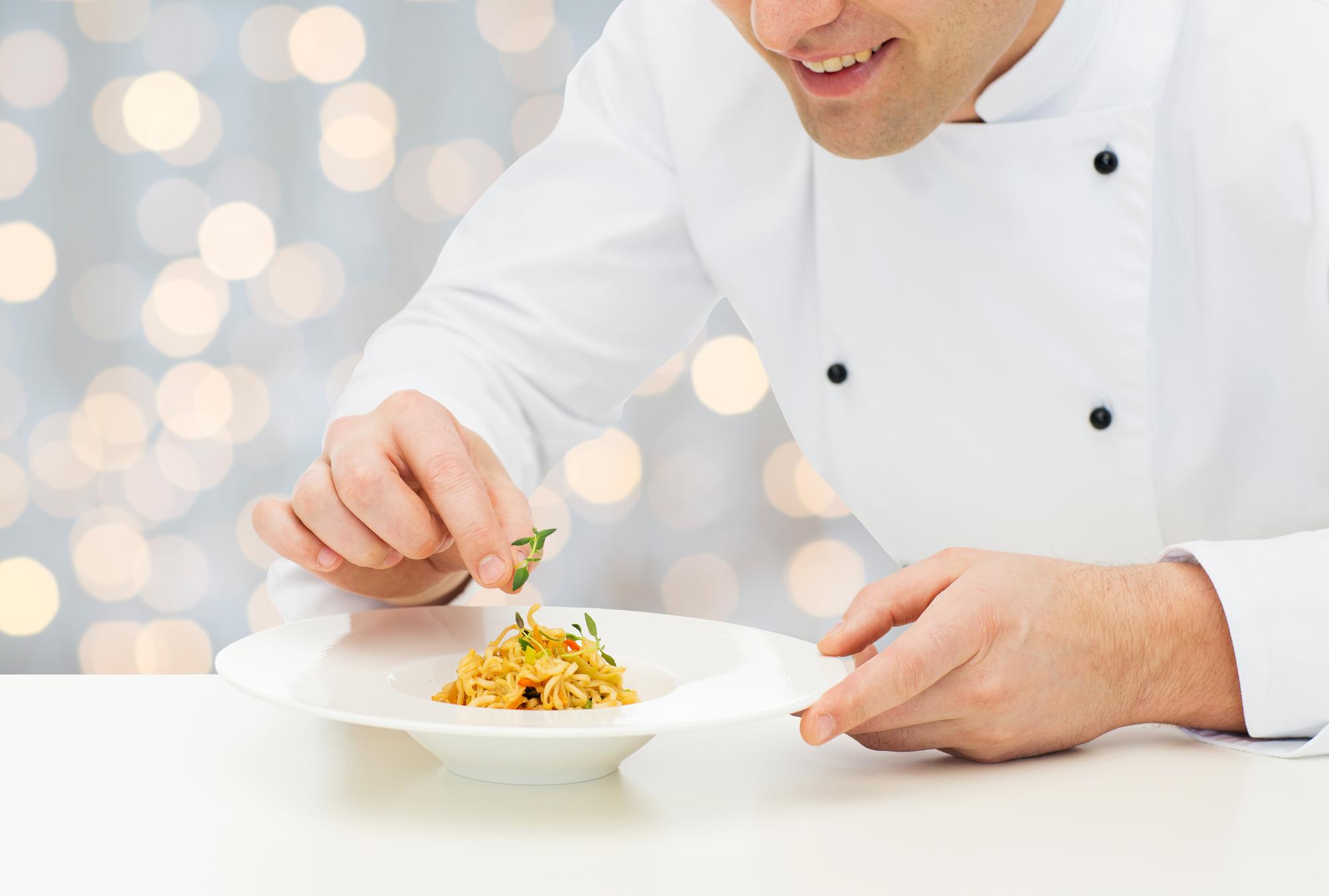 Chef arranging a plated dish on a wooden table
